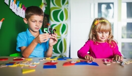 a boy and a girl playing with magnets on a table